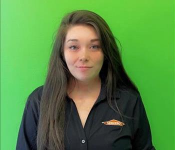 young woman in a black SERVPRO shirt in front of a green background. 